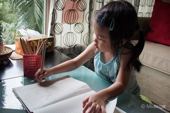 Occupying herself with coloring activities.