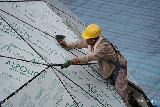 A worker aligning the plastic sheets covering the badminton dome.