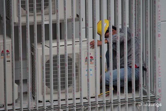 A fellow resident remarked that the workers are testing the air conditioning unit's compressor for gas pressure,