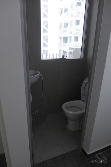 The toilet adjacent to the kitchen.