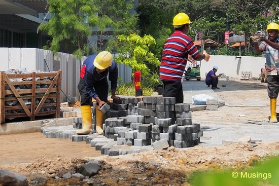 Workers laying and tossing bricks near the main entrance.