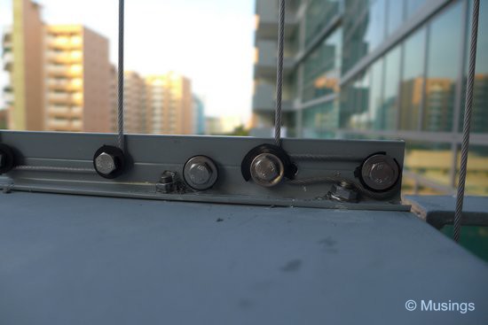 Each steel wire is secured and further tightened by screws at the pane's base. 