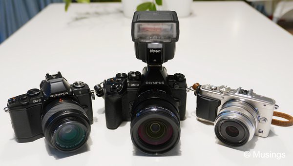 Three of the four m4/3 cameras I've got now in possession; the 3.5 year old E-M5, the E-M1 with the 12-40mm and the Nissin i40 flashgun, and the E-PL6.